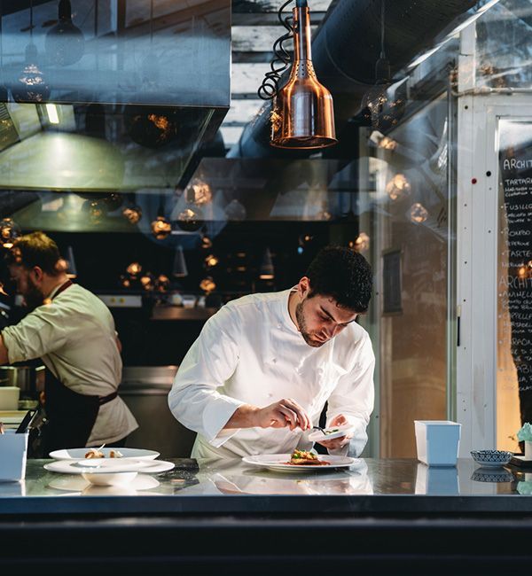 A chef skilfully prepares ingredients in a bustling restaurant kitchen, surrounded by cooking equipment and fresh produce.