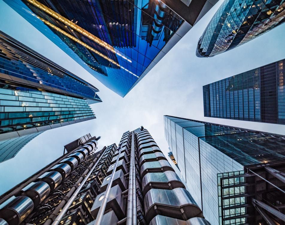View looking up at tall glass office buildings in London, showcasing modern architecture against a clear sky.